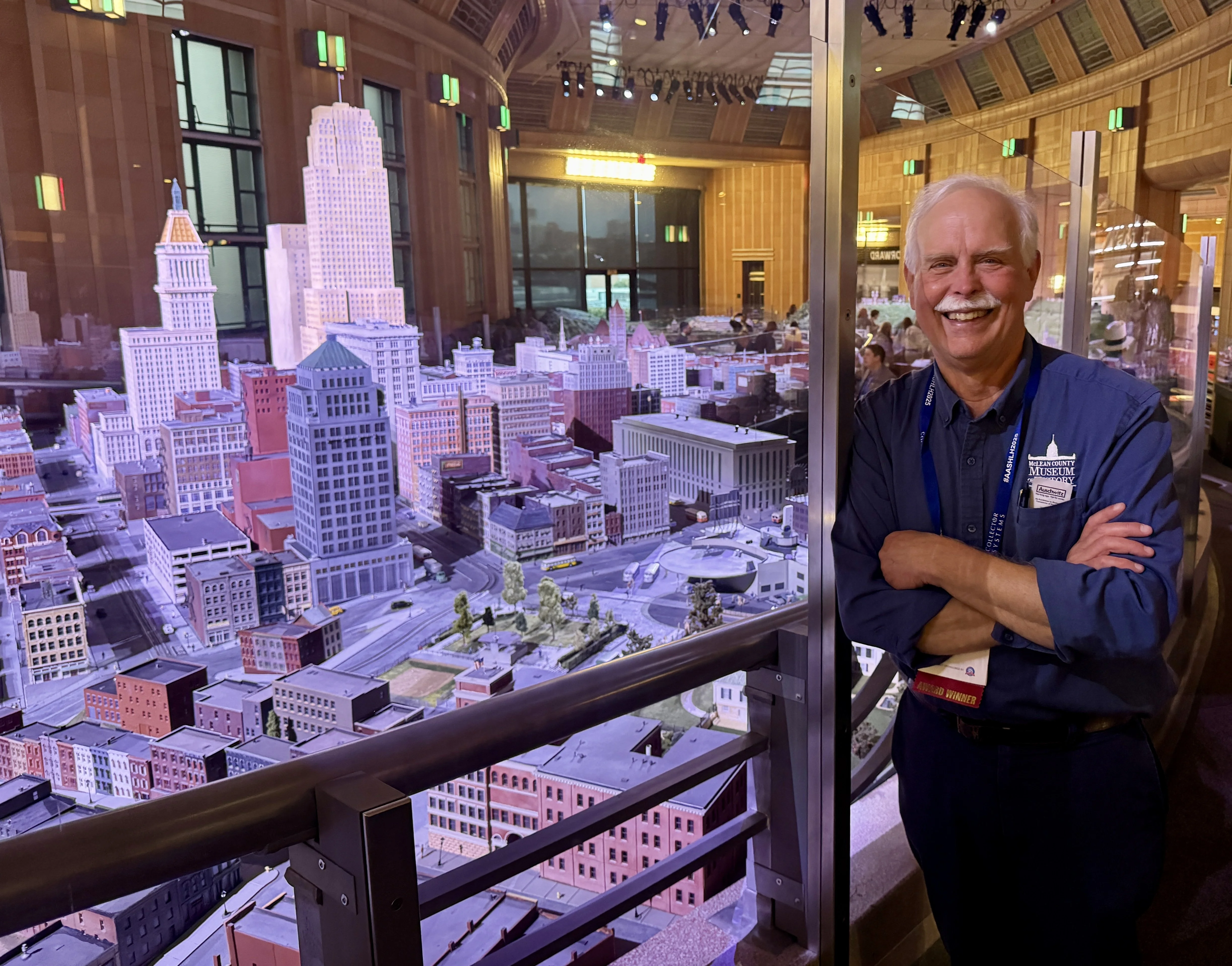 Mike poses next to an elaborate model train display of Cincinnati.