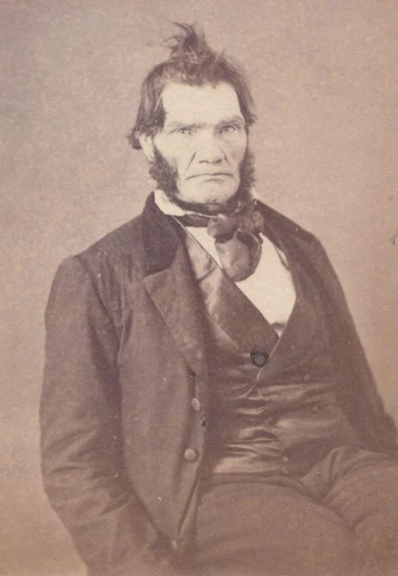 portrait of a white man in a three piece suit with very messy dark hair and massive sideburns